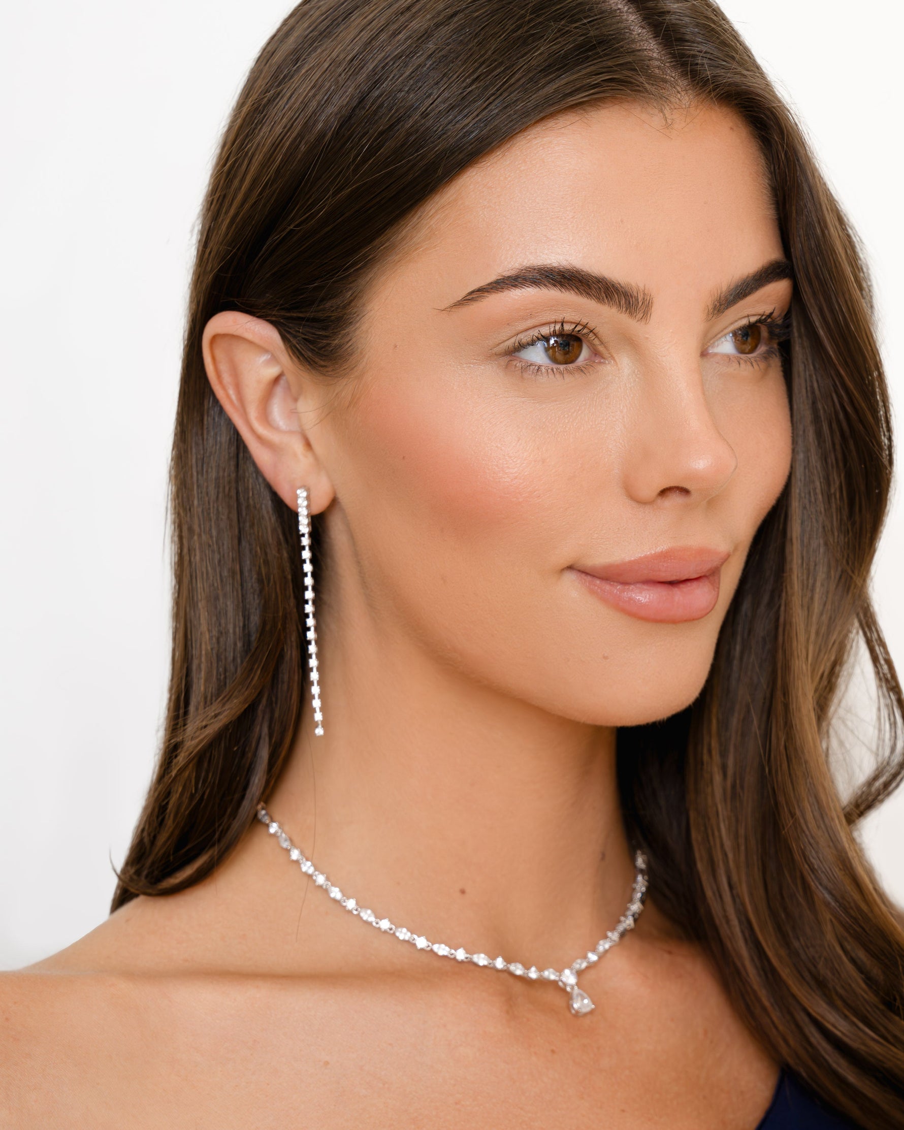 Model wearing sterling silver drop earrings and a diamond tennis necklace