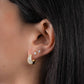 Model wearing diamond earrings featuring small gold huggie hoops