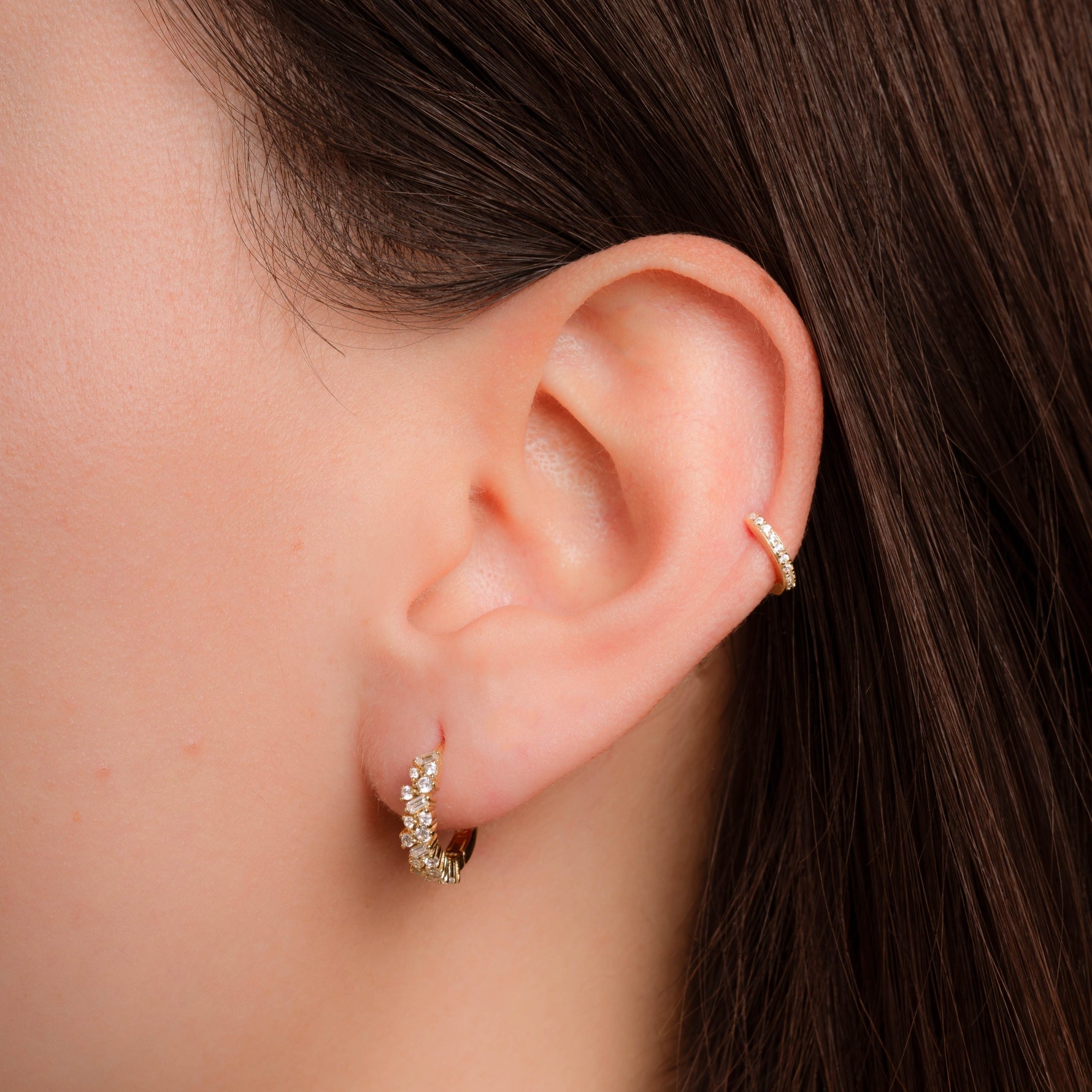Model wearing diamond huggie earrings plated in 14k gold