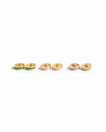 closeup image of our stripe gold diamond huggies in 3 different variants, emerald, white cz, and aquamarine