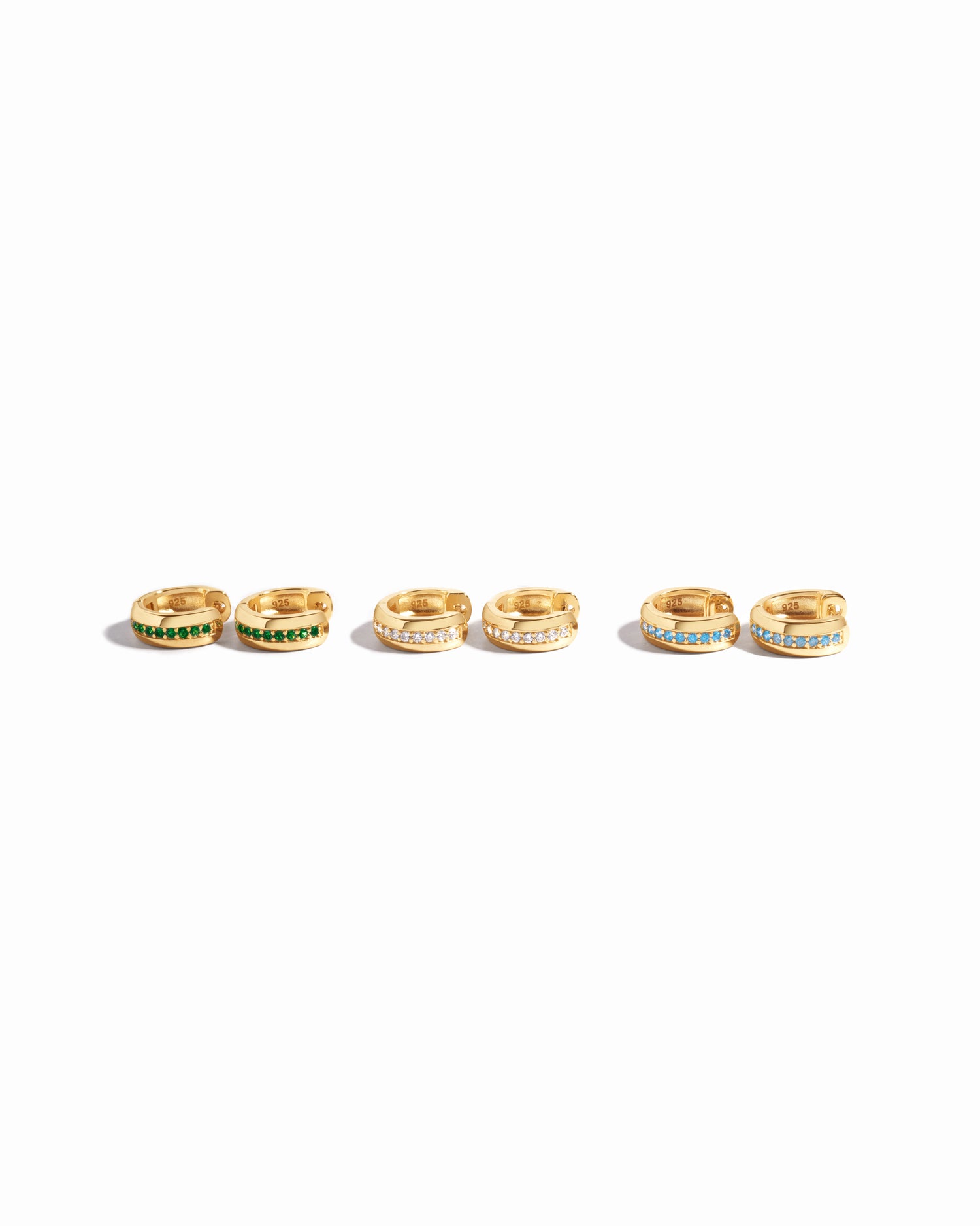 image showcasing our stripe diamond huggie earrings and its different variants including, emerald, white cz, and aquamarine
