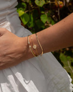 Model wearing gold celestial jewelry featuring a celestial bracelet, a gold chain bracelet and a bangle bracelet 