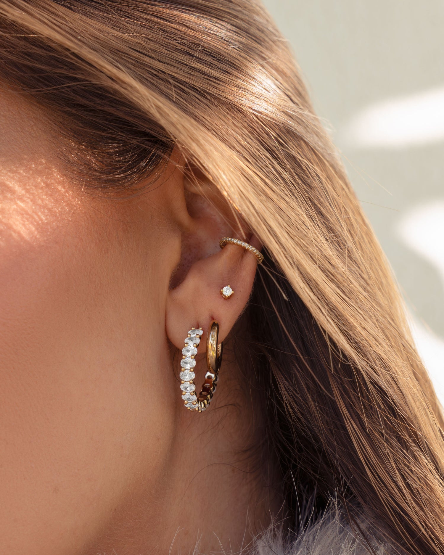 Model wearing 2.5mm stud earring with gold hoops, and oval diamond hoops