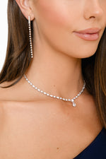 Close-up of a woman wearing a diamond necklace and earrings.