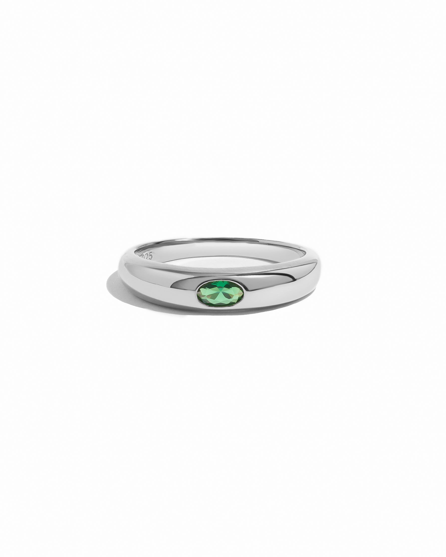 Silver ring with an emerald green gemstone on a white background