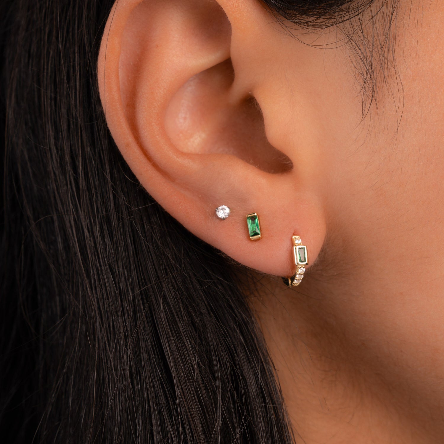 Model wearing birthstone jewelry featuring emerald stud earrings