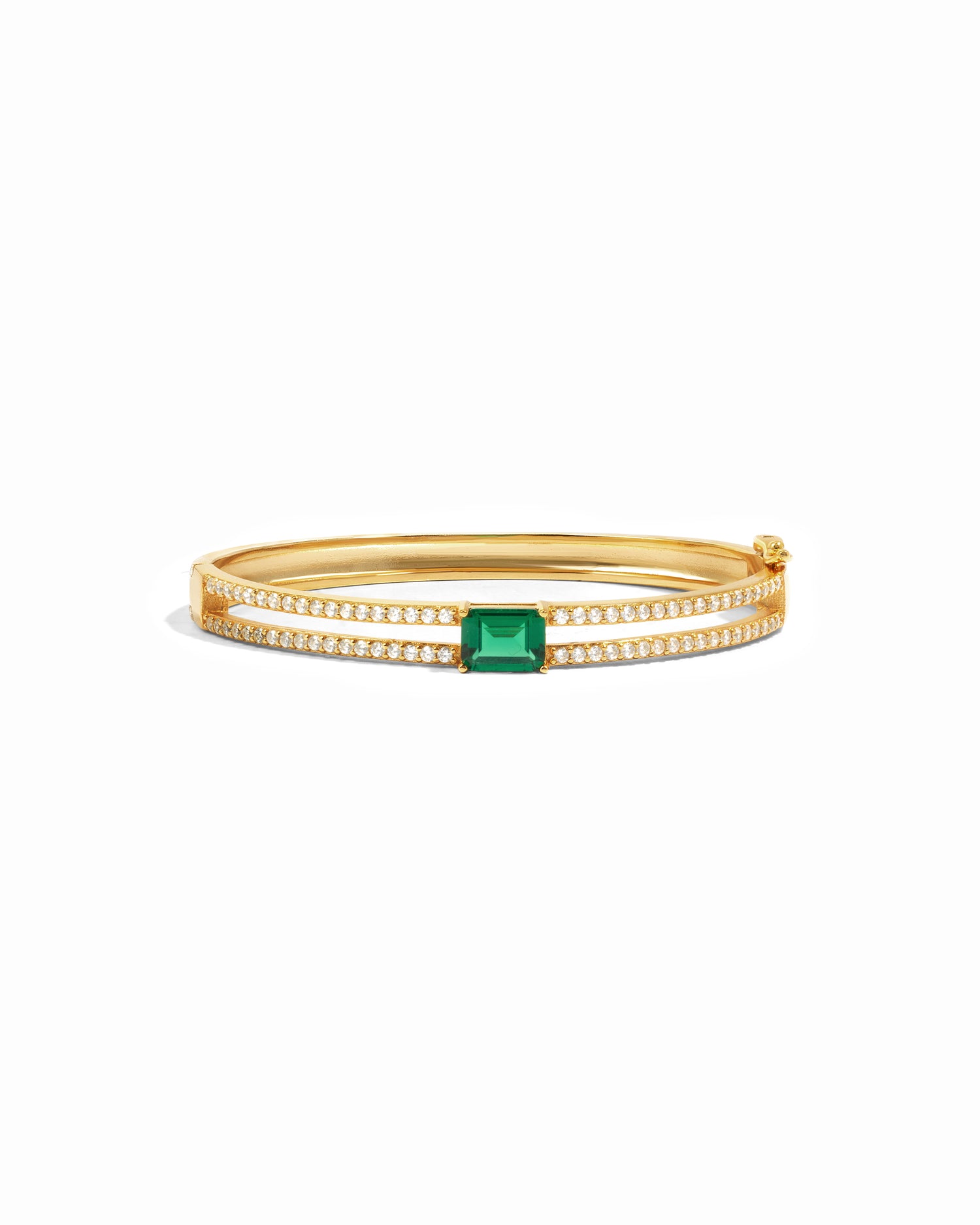 Gold bangle bracelet with a emerald green gemstone on a white background