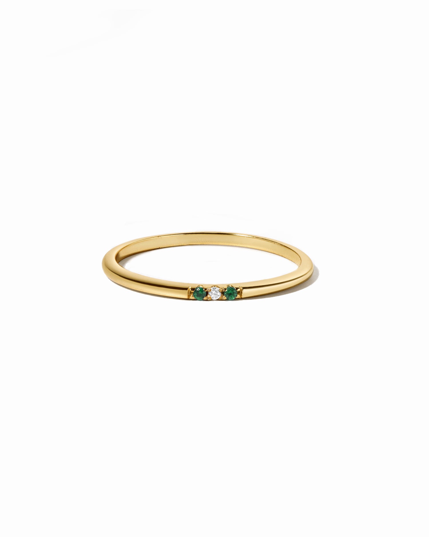 Gold ring with green gemstones on a white background