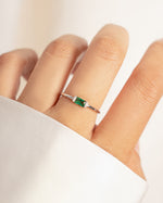 model wearing sterling silver minimalist baguette cz ring with emerald green center stone