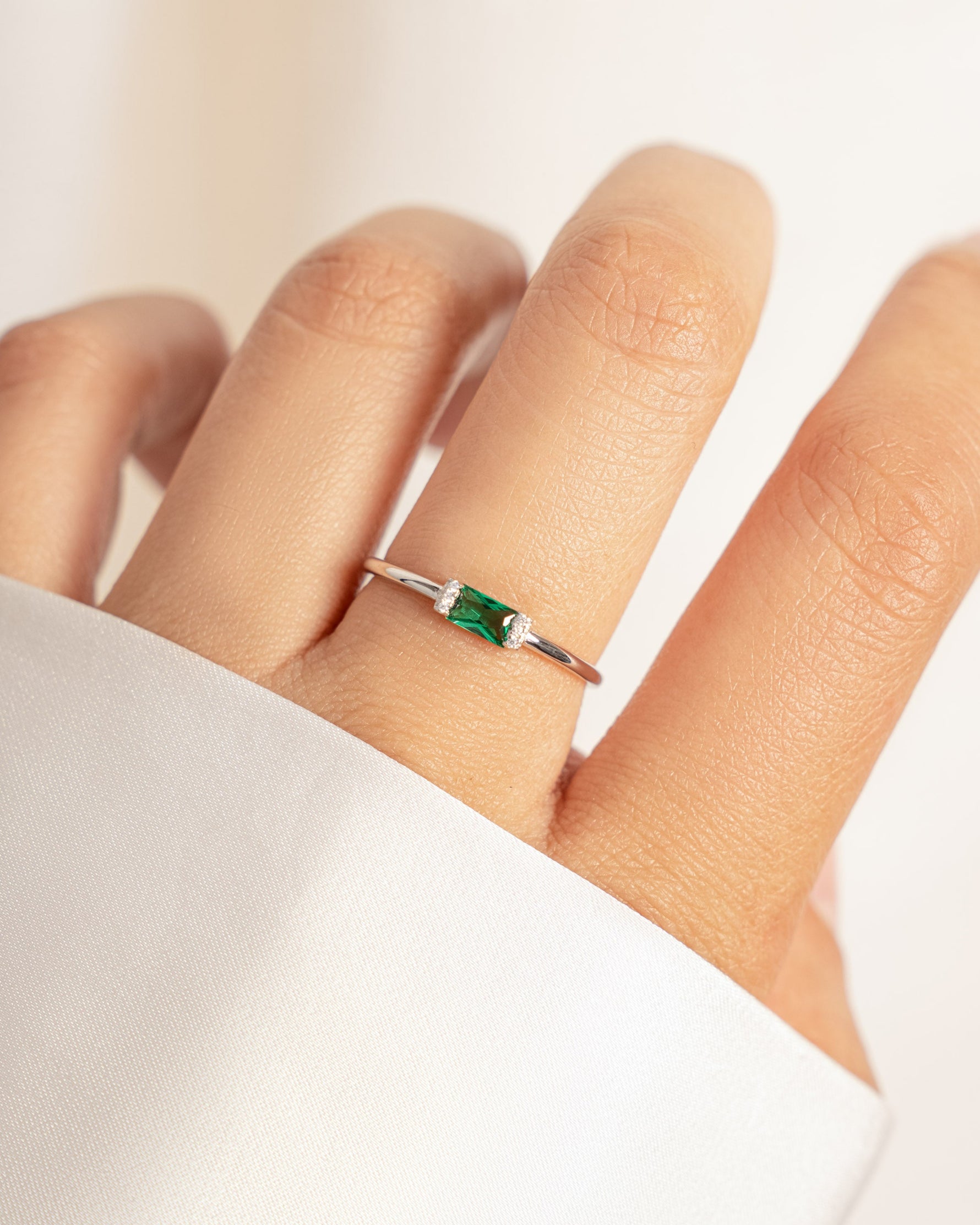 model wearing sterling silver minimalist baguette cz ring with emerald green center stone