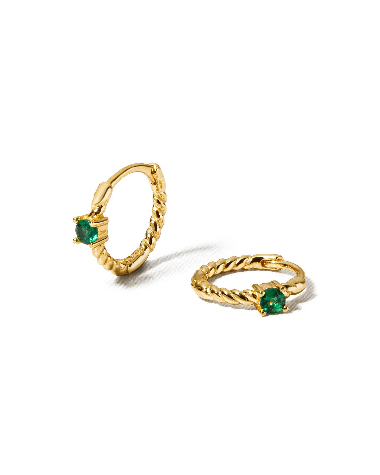 Small hoop earrings with a spiral design with emerald gemstones on a white background