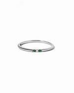 Silver ring with green gemstones on a white background