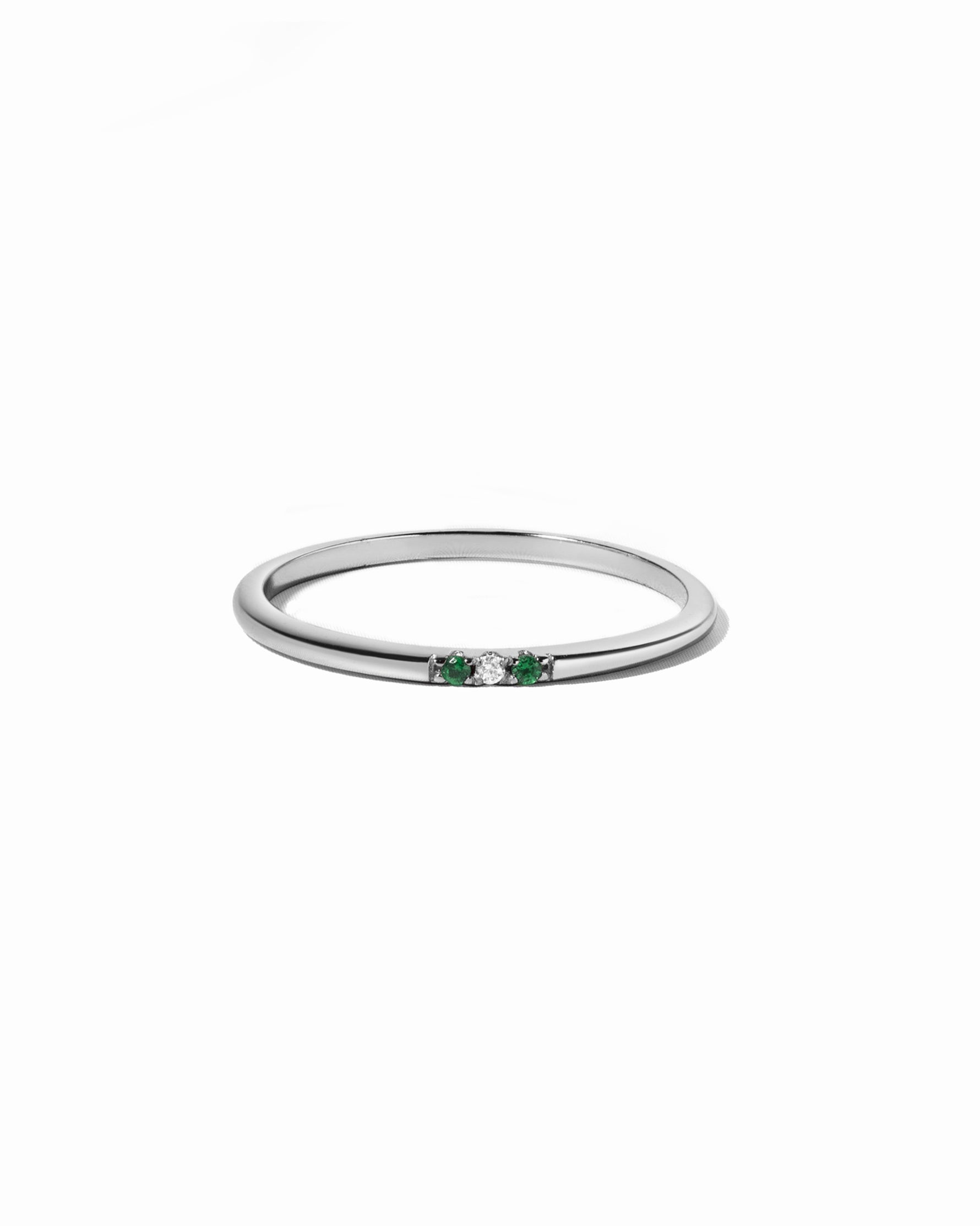 Silver ring with green gemstones on a white background