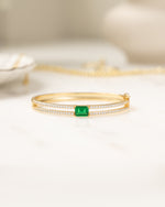 Gold gemstone bracelet featuring a bangle bracelet design and an emerald birthstone 