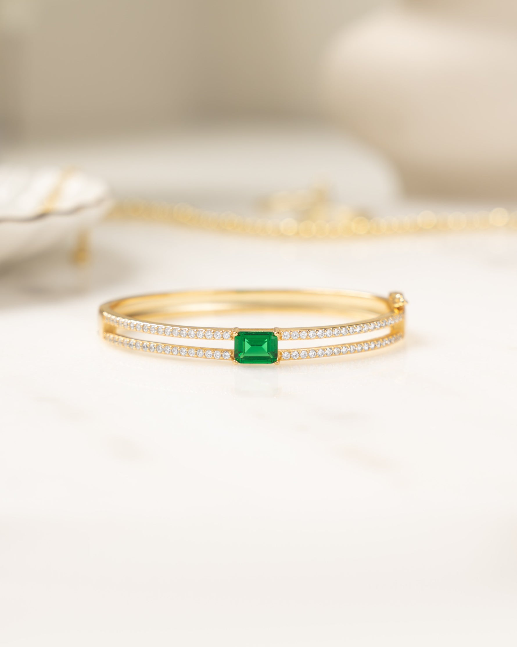 Gold gemstone bracelet featuring a bangle bracelet design and an emerald birthstone 