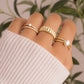 model wearing gold rings featuring a cubic zirconia stone diamond eternity band, and opal solitaire stone on an cz eternity band, a gold statement ring, and an opal oval statement ring.