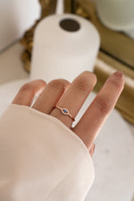 model wearing rose gold evil eye ring with cz stones and a blue gemstone