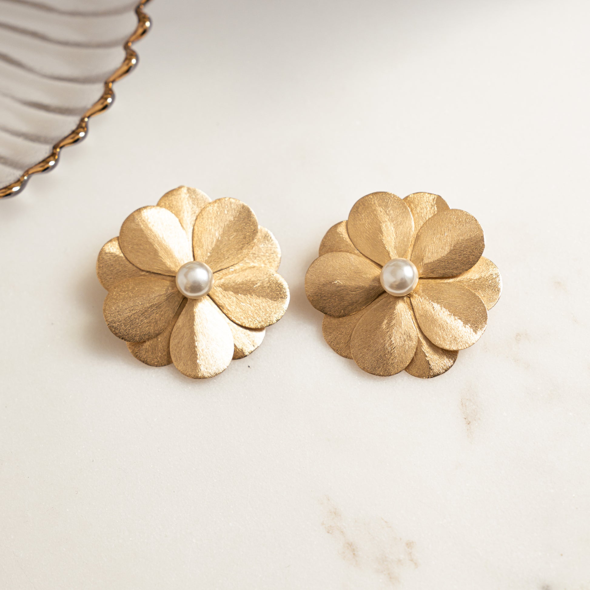 closeup image of boho earrings featuring gold floral stud earrings
