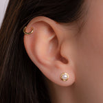Model wearing pearl jewelry featuring a dainty stud earring and a mini gold hoop