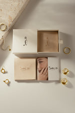 Sami Jewels branded gift boxes and jewelry packaging displayed with gold rings and earrings.