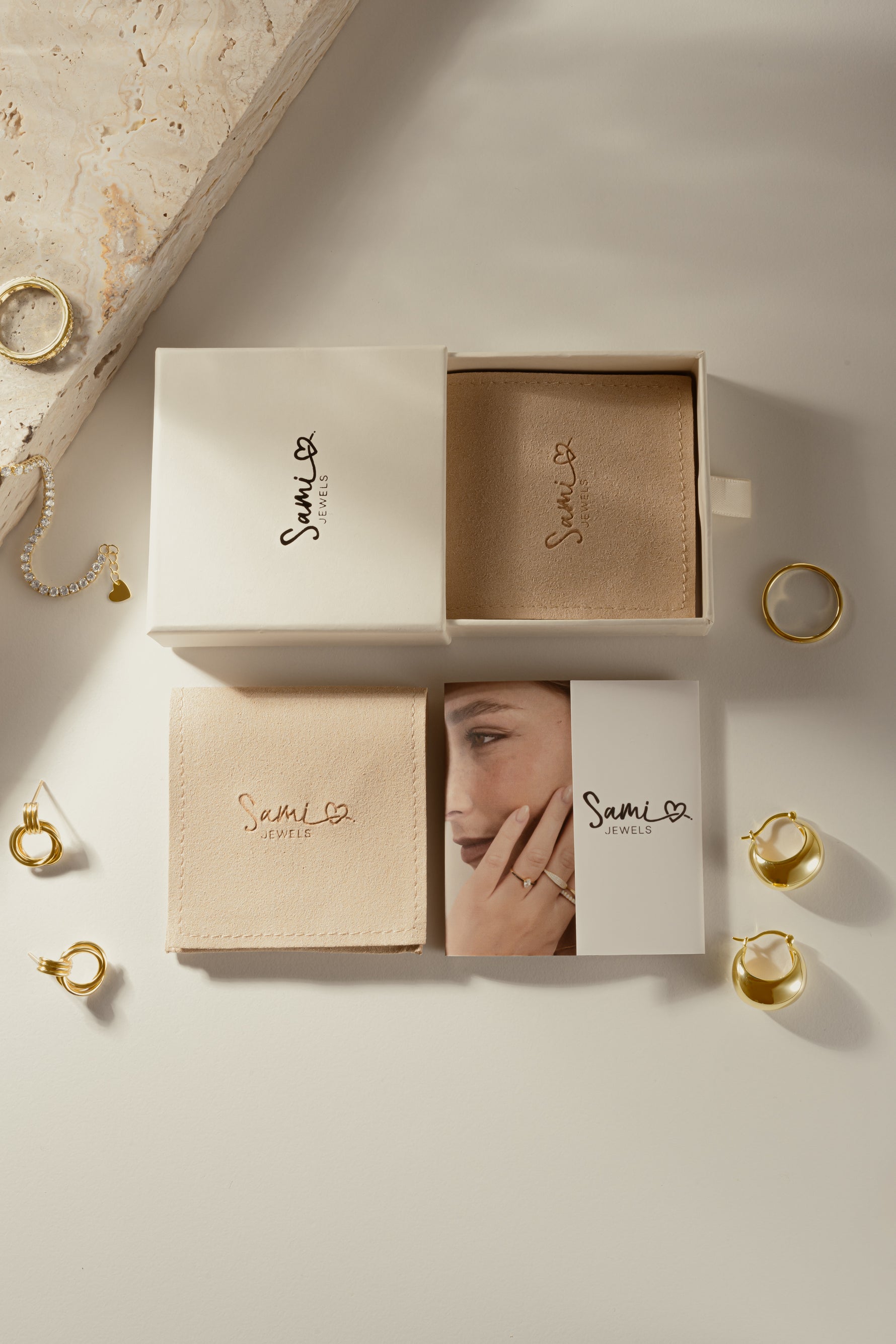 Sami Jewels branded gift boxes and jewelry packaging displayed with gold rings and earrings.