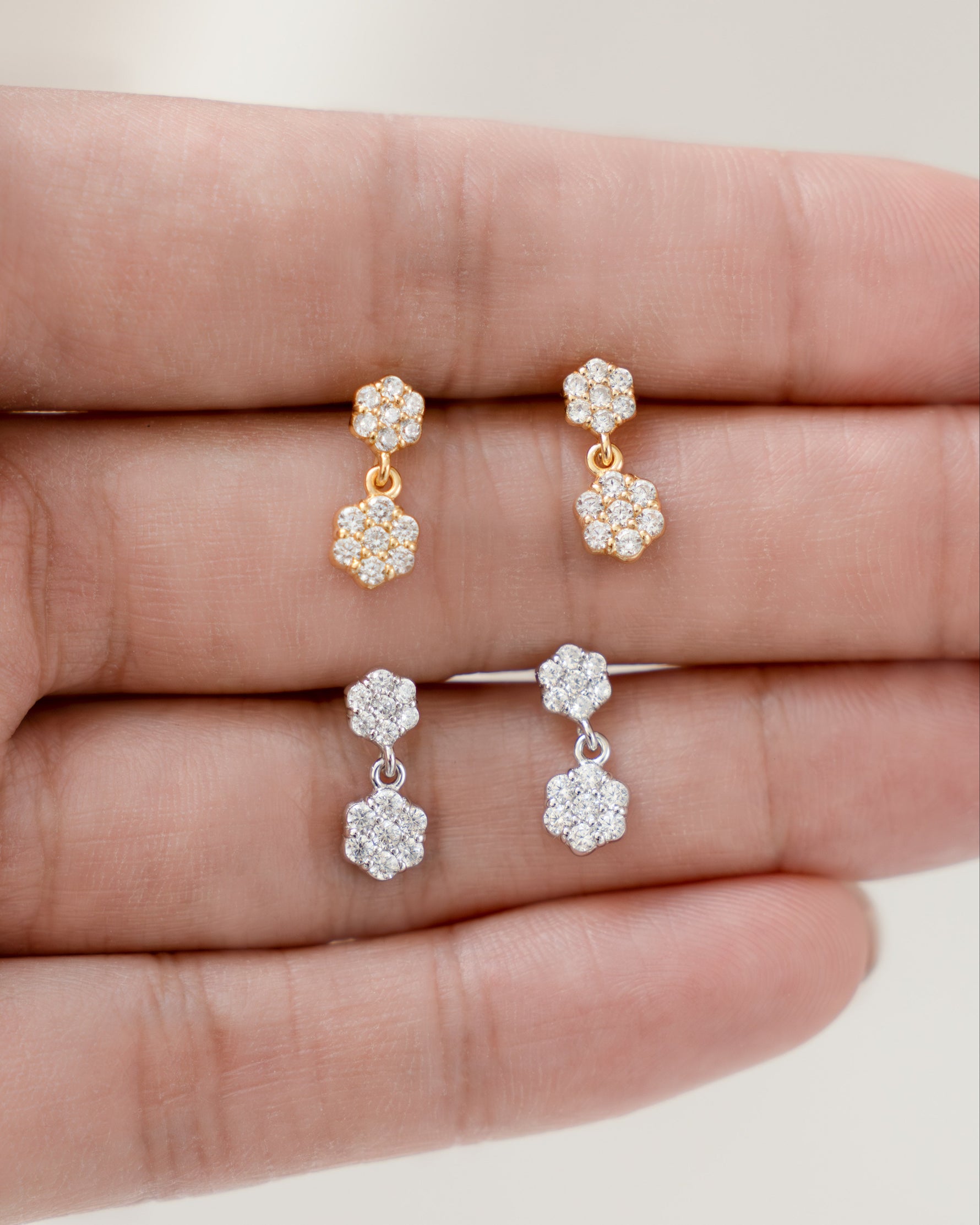 Tiny earrings with a charm earring design displayed on a hand against a neutral background