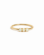 Gold ring with three small opal stones on a white background