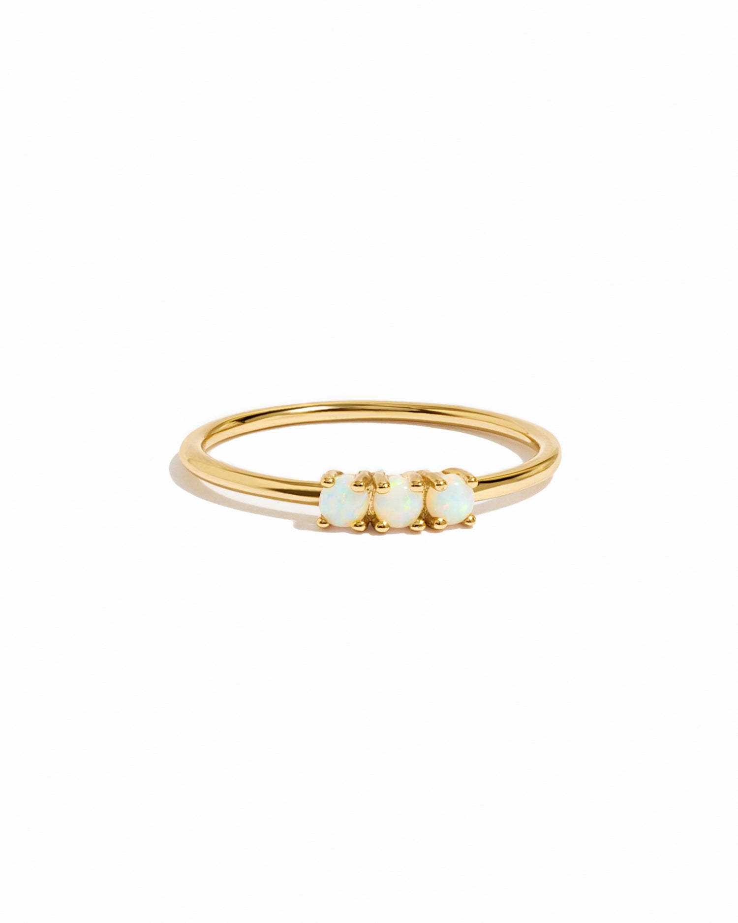 Gold ring with three small opal stones on a white background