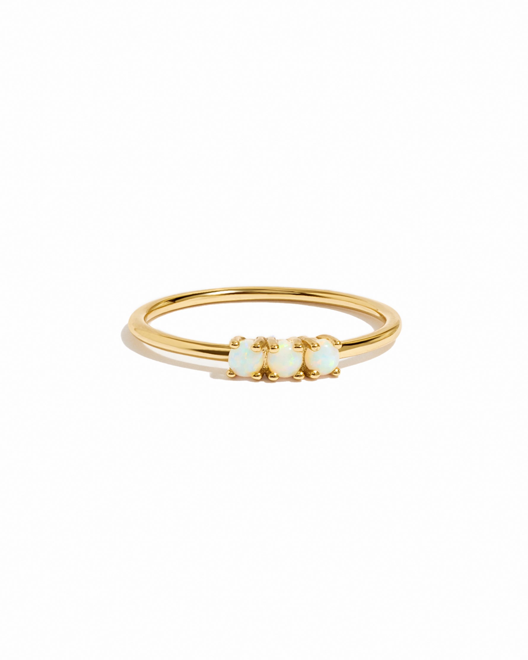 Gold ring with three small opal stones on a white background