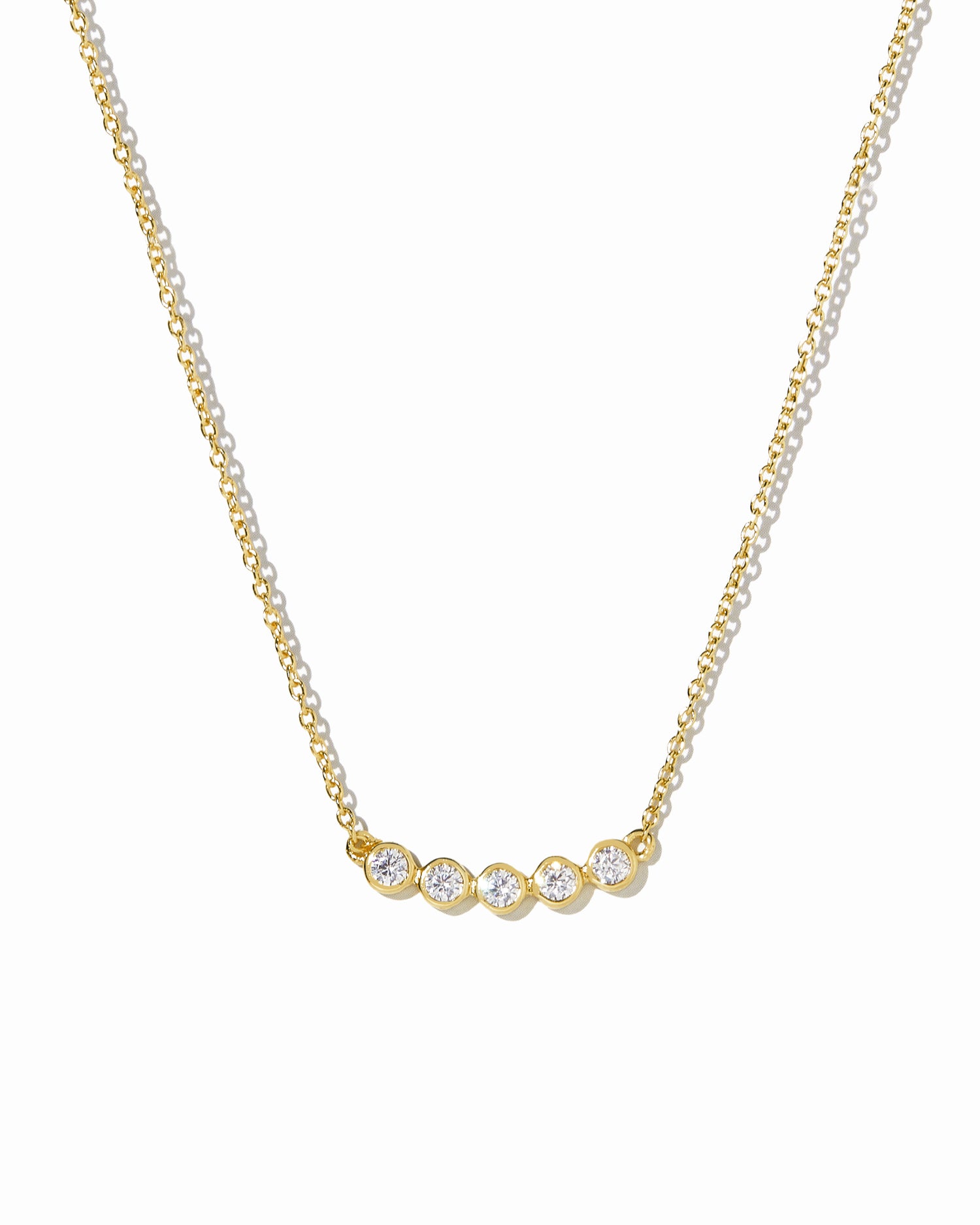 Gold necklace with 5 small diamonds on a white background