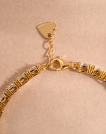 Gold adjustable bracelet with a lobster clasp closure on a neutral background