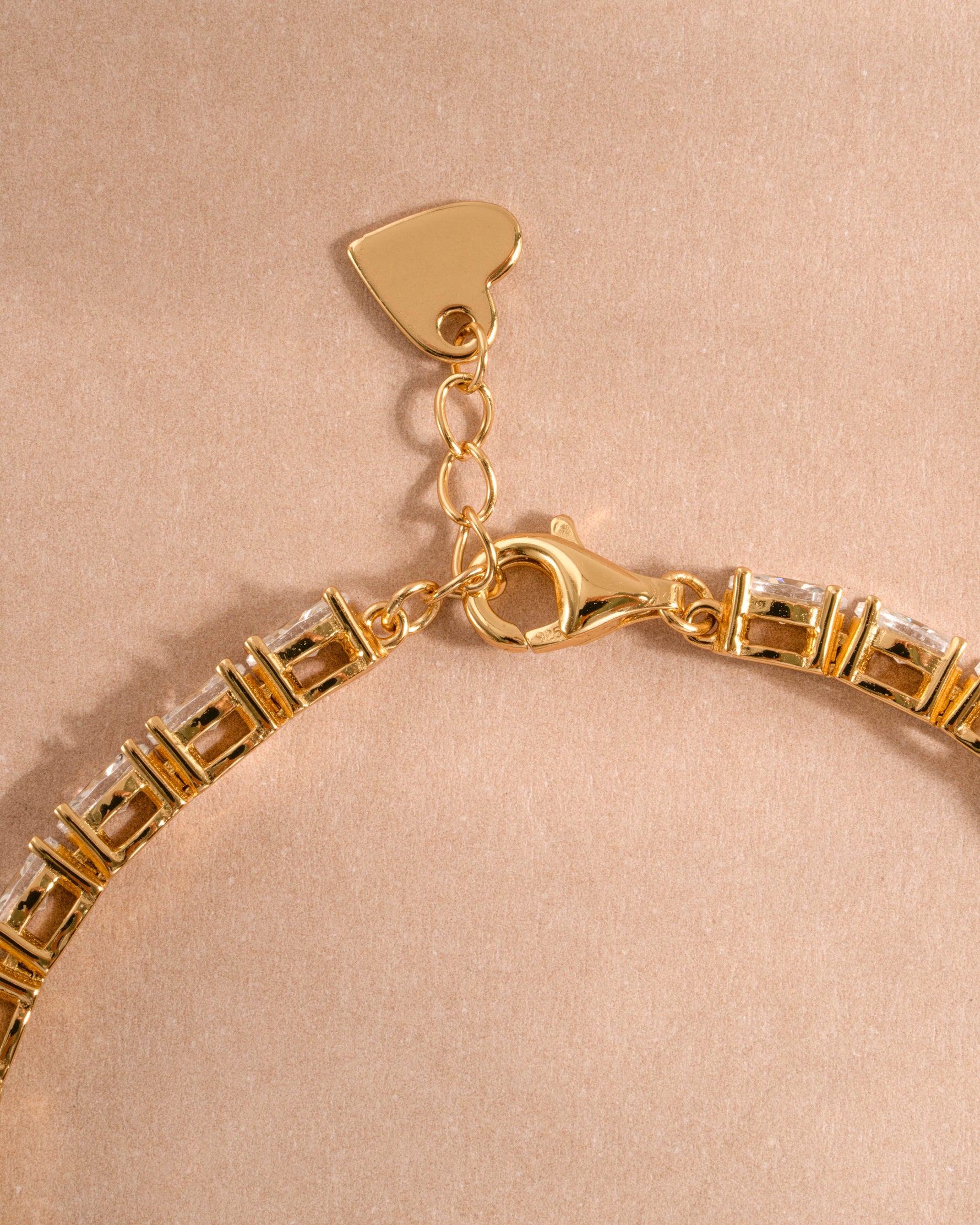 Gold adjustable bracelet with a lobster clasp closure on a neutral background