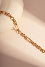 Gold chain paperclip bracelet on a light pink background