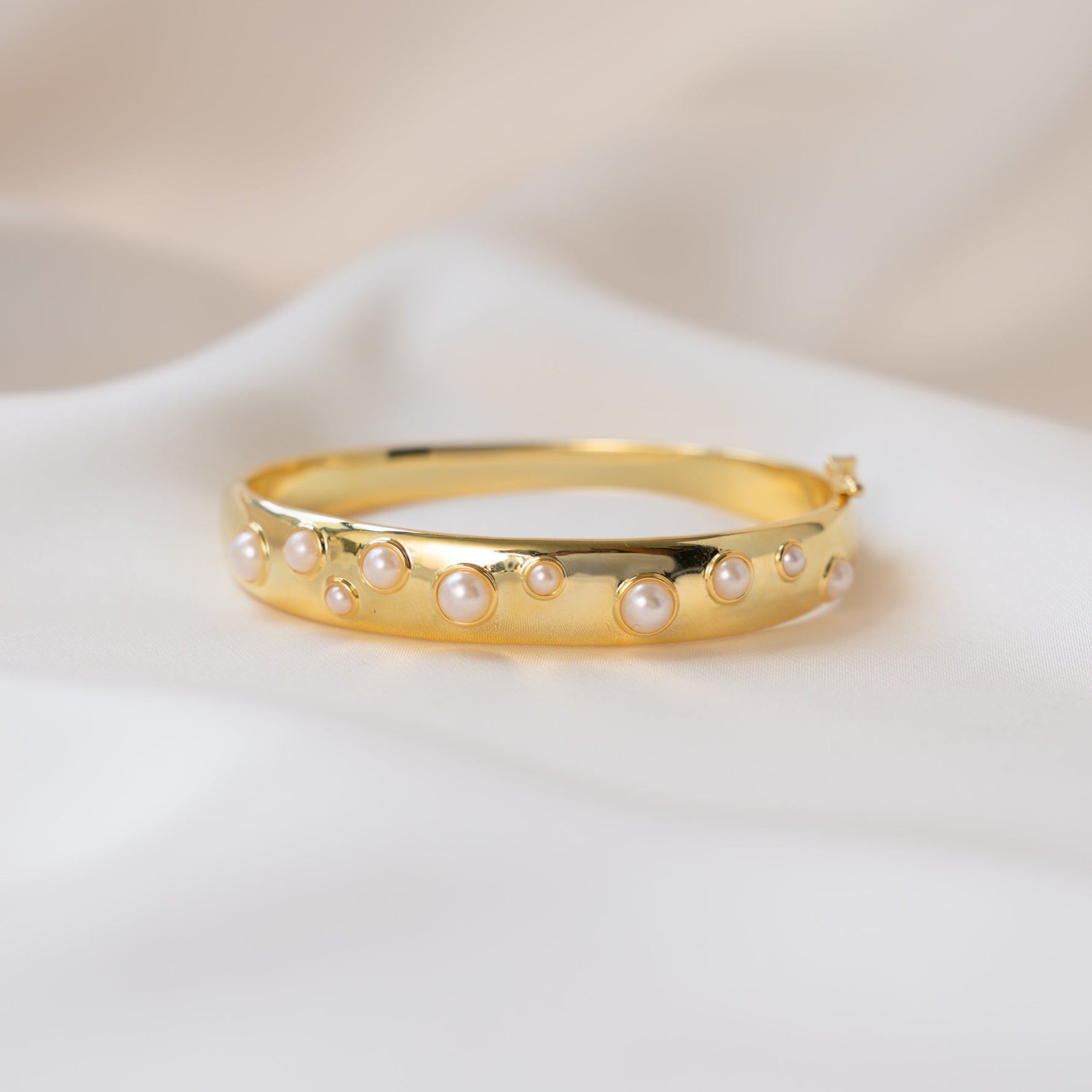 closeup image of thick bangle bracelet with studded pearl design