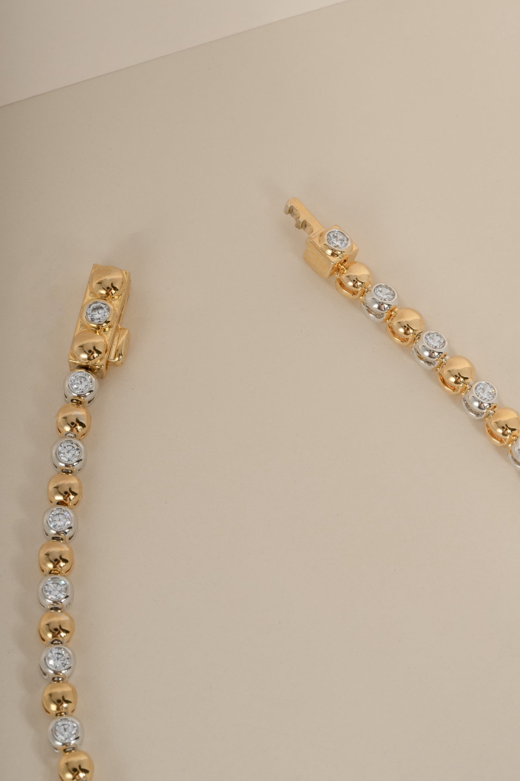 Gold and silver beaded diamond two tone necklace with a box clasp closure style on a beige background