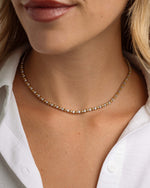 Close-up of mixed metal jewelry on model featuring a gold and silver diamond necklace 