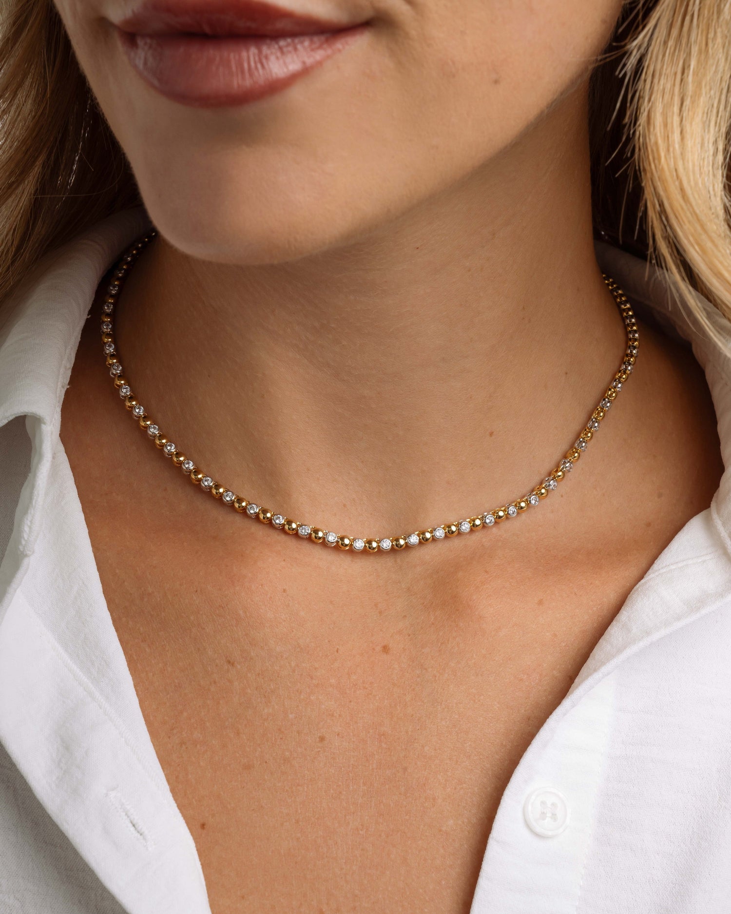 Close-up of mixed metal jewelry on model featuring a gold and silver diamond necklace 