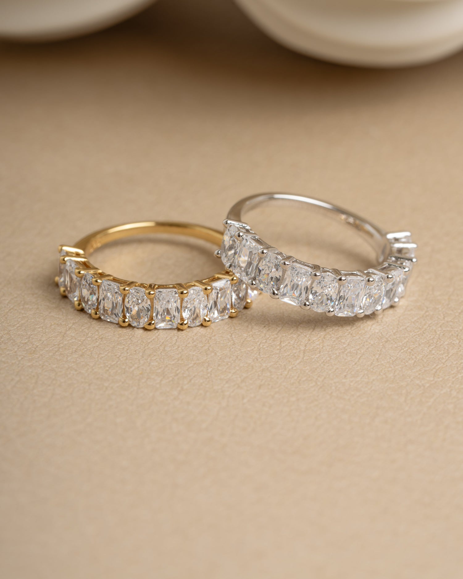 Gold wedding band and sterling silver promise ring on beige surface