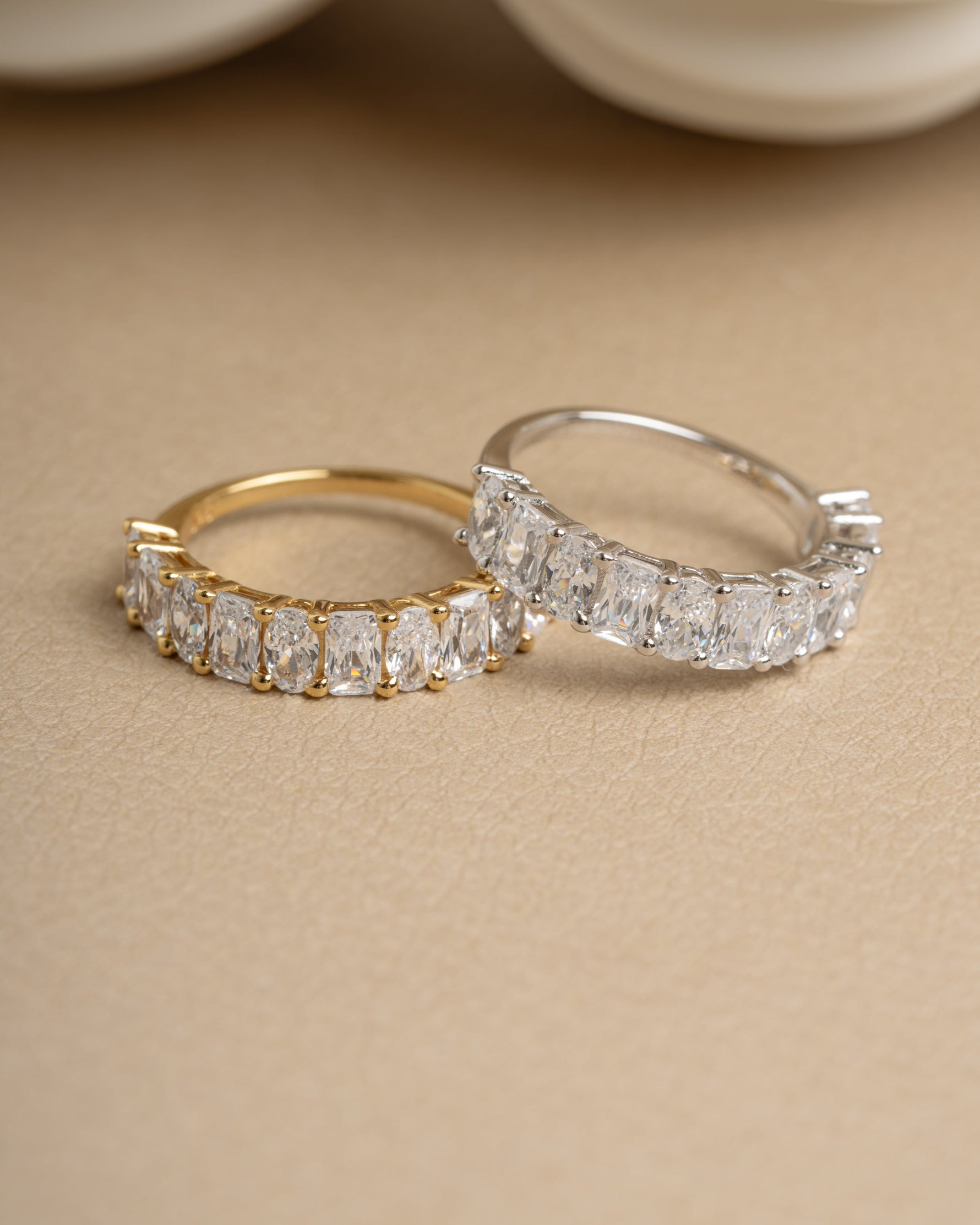 Gold wedding band and sterling silver promise ring on beige surface