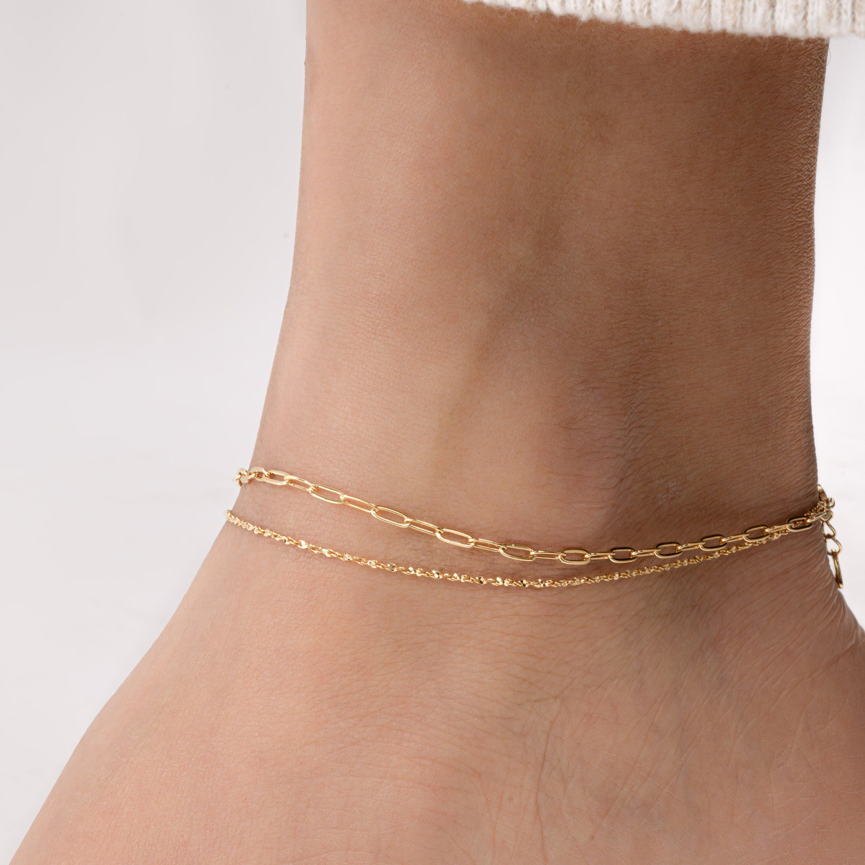 Model wearing a delicate gold anklet set