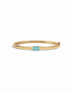 Gold bangle bracelet with a aquamarine gemstone on a white background