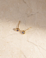 Gold small earrings with the march birthstone on a marble background