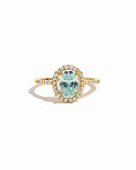 Gold halo ring with a turquoise gemstone on a white background