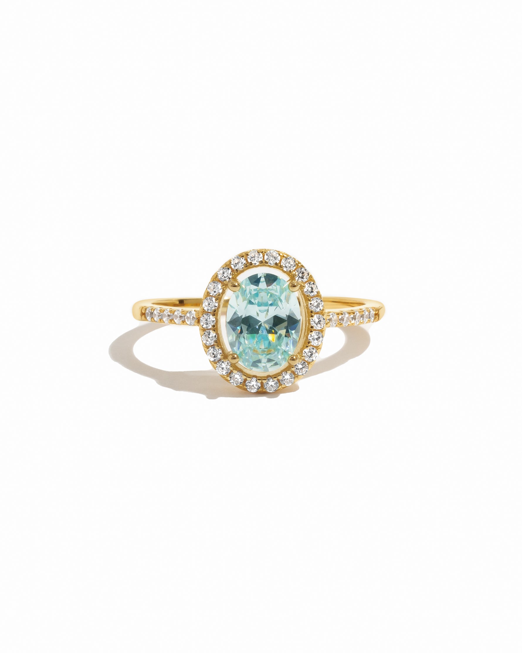 Gold halo ring with a turquoise gemstone on a white background