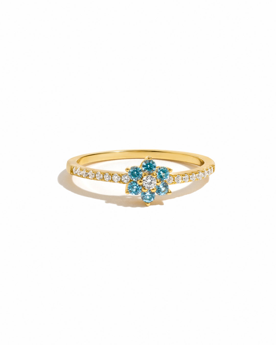 gold dainty stackable ring with aquamarine flower on a white background