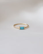 dainty gold baguette ring with cz diamonds and a turquoise gemstone on a white background