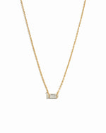 Delicate gold baguette stone necklace on white background.