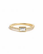 Gold ring with a central gemstone and pave cubic zirconia stones on a white background