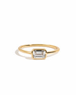 Gold ring with a baguette stone on a white background