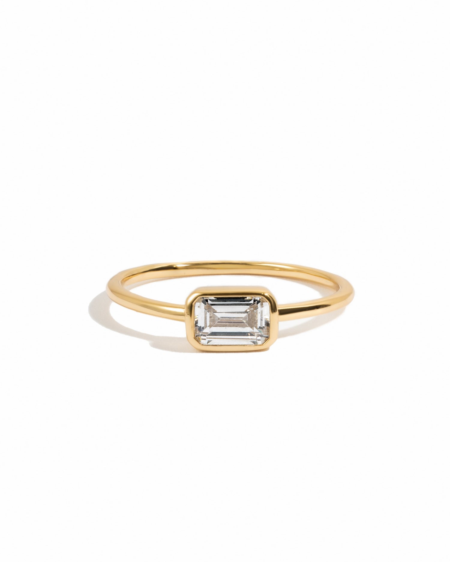 Gold ring with a baguette stone on a white background